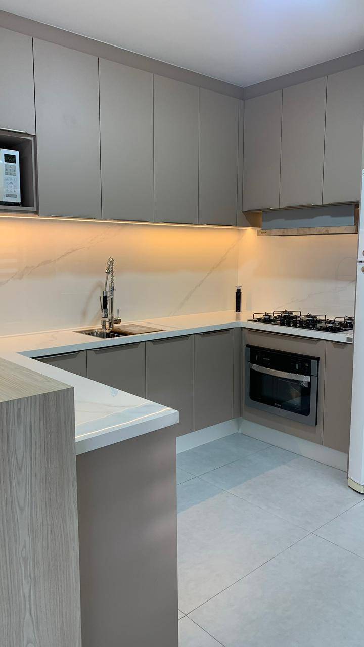 Cozinha com bancada em porcelanato e nichos iluminados.